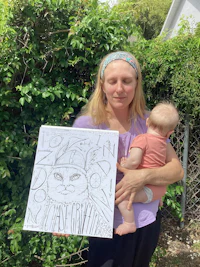 a woman holding a baby while holding a coloring book